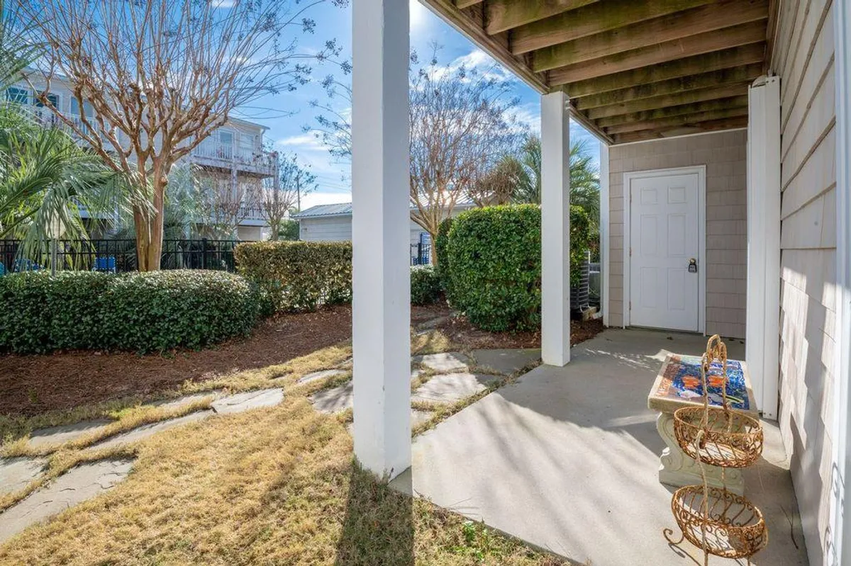 Another exterior angle featuring the front door, decorative bench, landscaped shrubs, and a pathway leading outward. The well-maintained space suggests comfort and ease for guests coming and going, with a subtle nod to relaxation and neighborhood charm.
