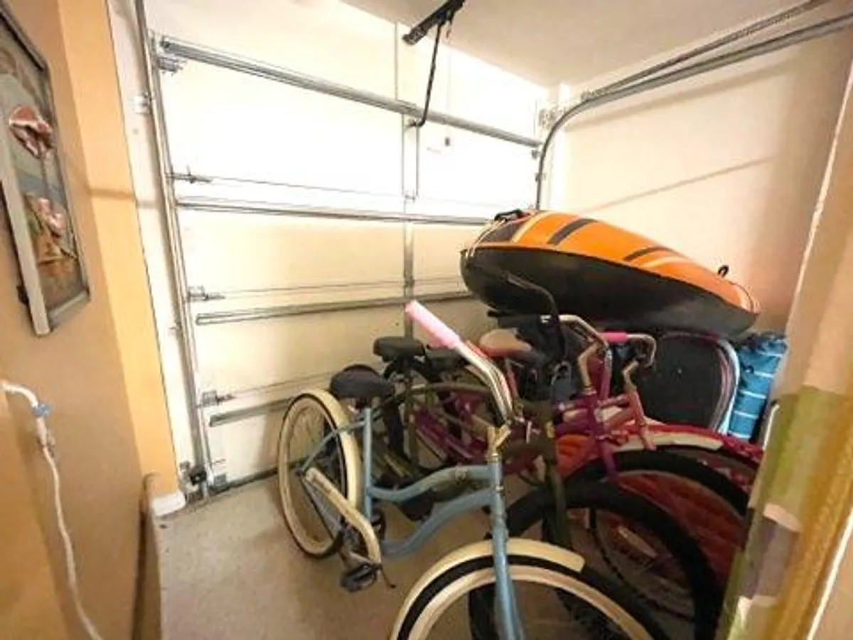 The garage is filled with recreational items, including bicycles and an inflatable boat, with the garage door as a backdrop. This image clearly establishes the garage's role as a storage hub for beach and adventure gear, ready for outings and family trips.