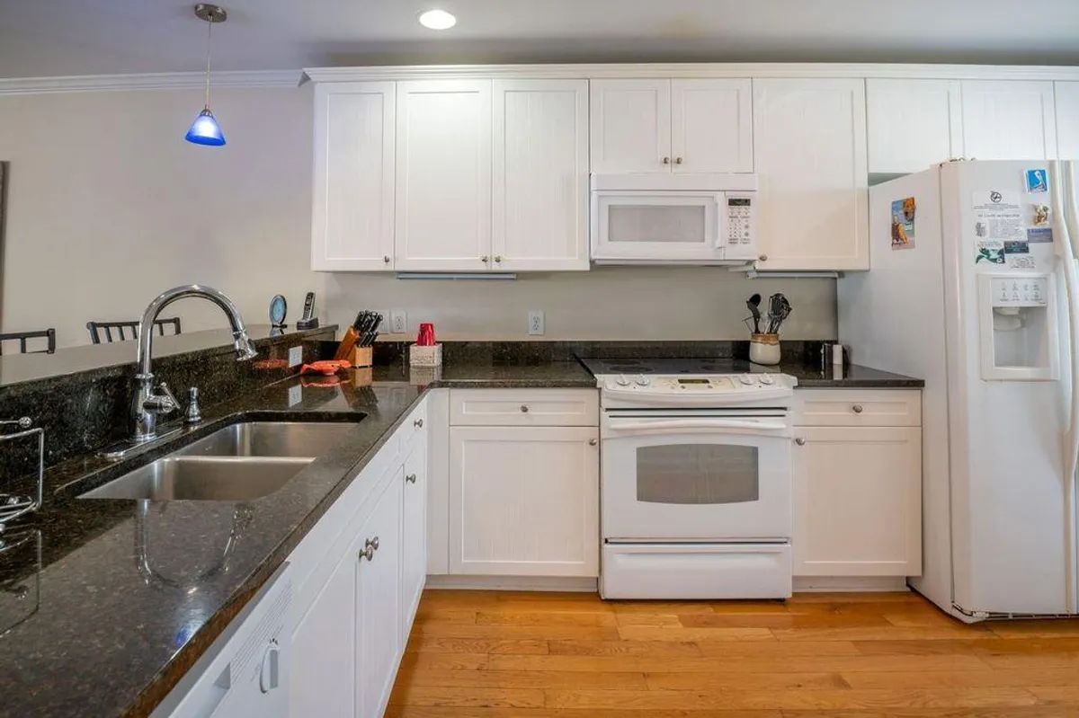 A spacious kitchen with a central island, white cabinetry, black granite countertops, and stainless steel appliances. The scene evokes a sense of togetherness, with subtle hints of holiday treats and family gatherings in the air.