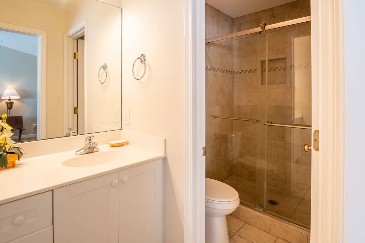 A modern bathroom with a sleek vanity, a glass-enclosed walk-in shower, and a large mirror. The finishes are crisp and the mood is calm and refreshing, ideal for unwinding after a day out.