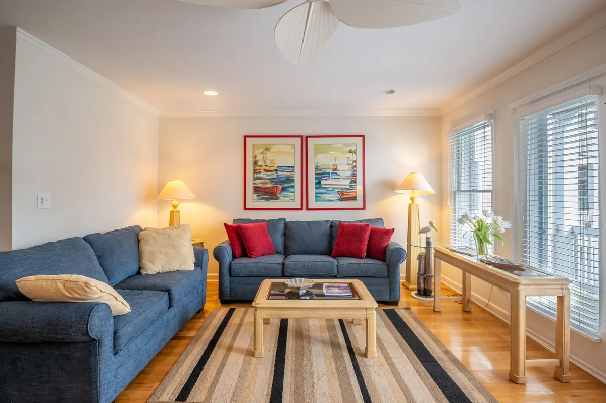 A cozy living room with a comfortable sofa, stylish coffee table, soft lighting from lamps, and windows filling the space with natural light. Artwork on the wall adds personality and charm, creating a space ideal for relaxation or socializing.